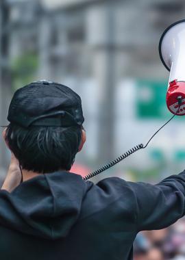 Mann mit Megaphone vor Menschenmenge